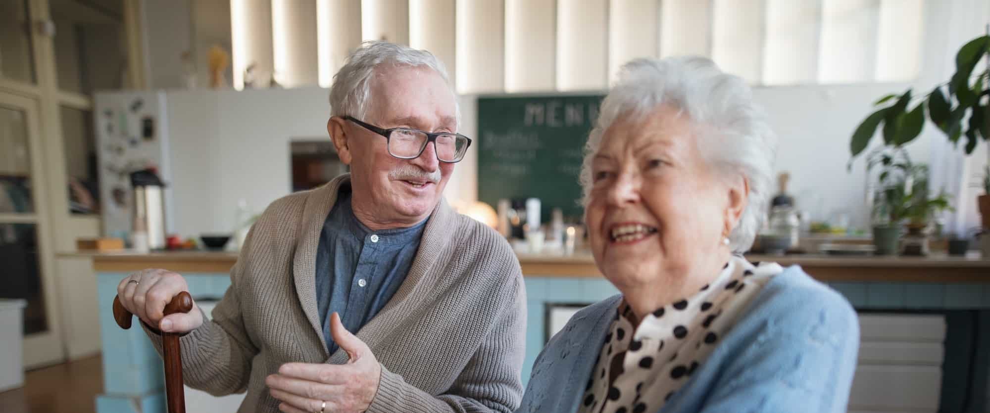 Smiling elderly woman and man enjoying breakfast in nursing home care center